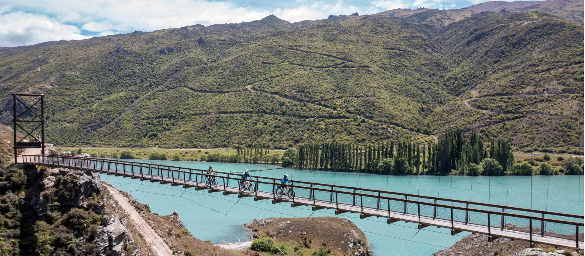 Cyclists riding across the Hugo Swingbridge on the Lake Dunstan Trail. | Geoff Marks