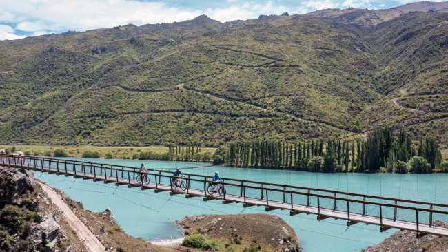 Cyclists riding across the Hugo Swingbridge on the Lake Dunstan Trail. | Geoff Marks