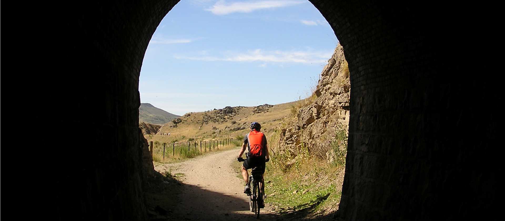 Cycling through a historic railway tunnel on the Otago Rail Trail